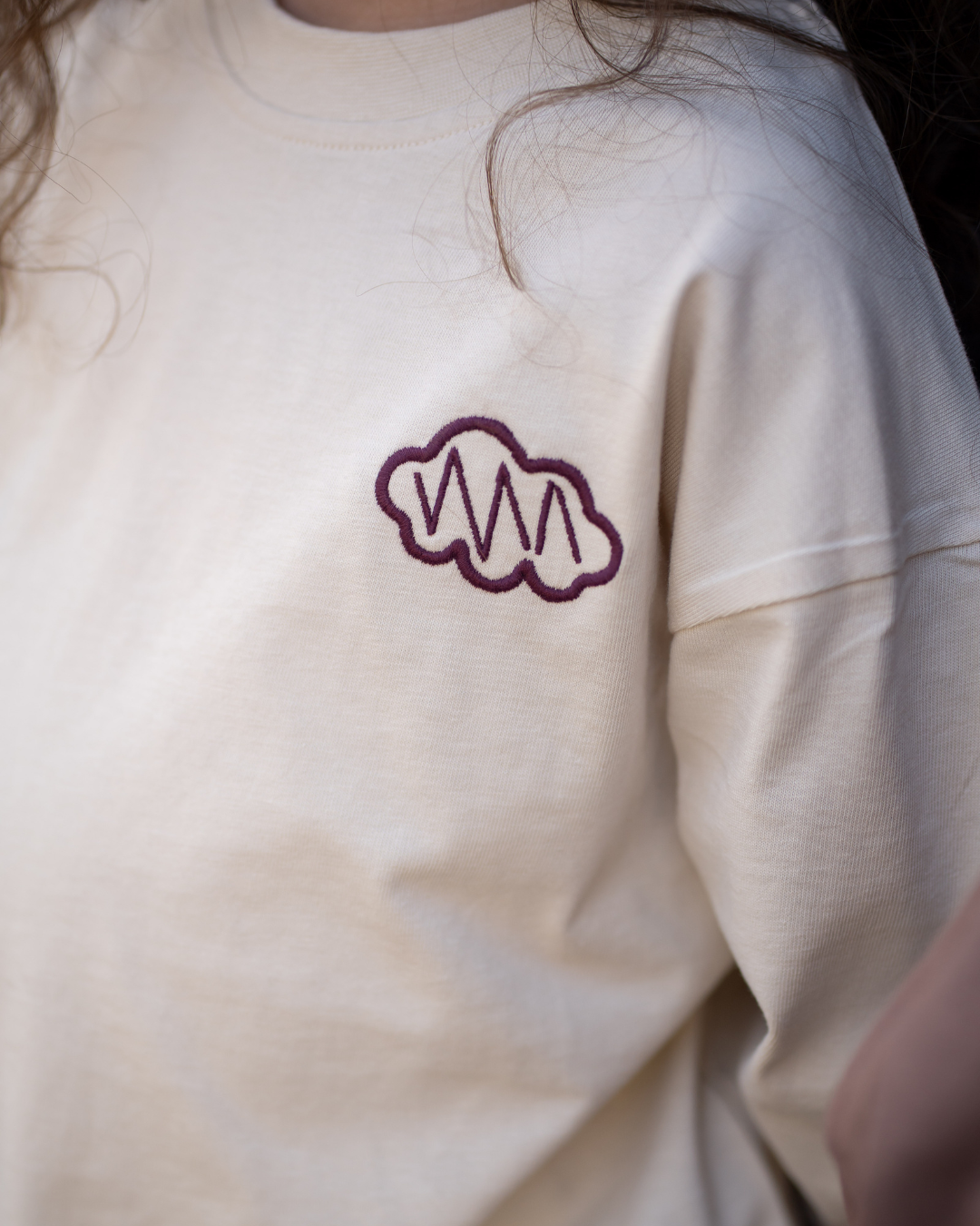 Nahaufnahme des cremefarbenen Daydream Longsleeve von Comfy Studios mit besticktem Wolken-Logo auf der Brust.