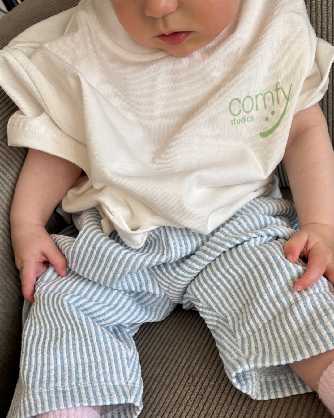 Weißes Comfy Studios Kindness Shirt mit grünem comfy-Logo vorn an einem Kleinkind – Oversize-Kindershirt aus Baumwolle.