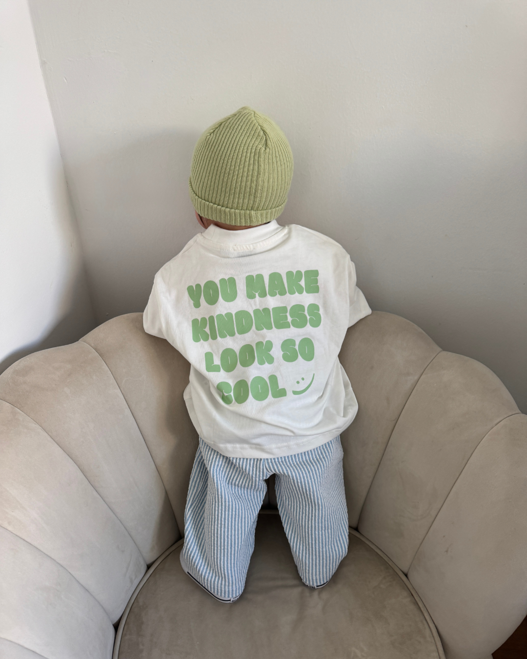 Rückansicht Kindness Shirt in Creme mit grünem Statement-Print „You make kindness look so cool" an einem Kind.