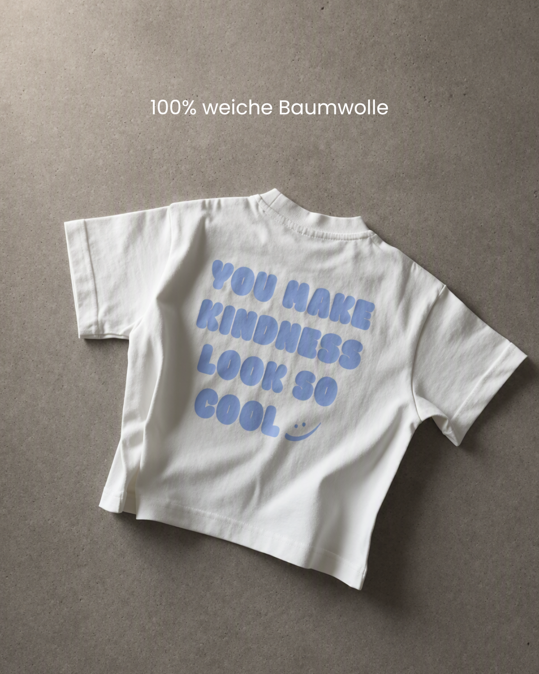Flat Lay Rückansicht des Kindness Shirts in Blau mit blauem Print „You Make Kindness Look So Cool" auf Betonhintergrund – 100% weiche Baumwolle