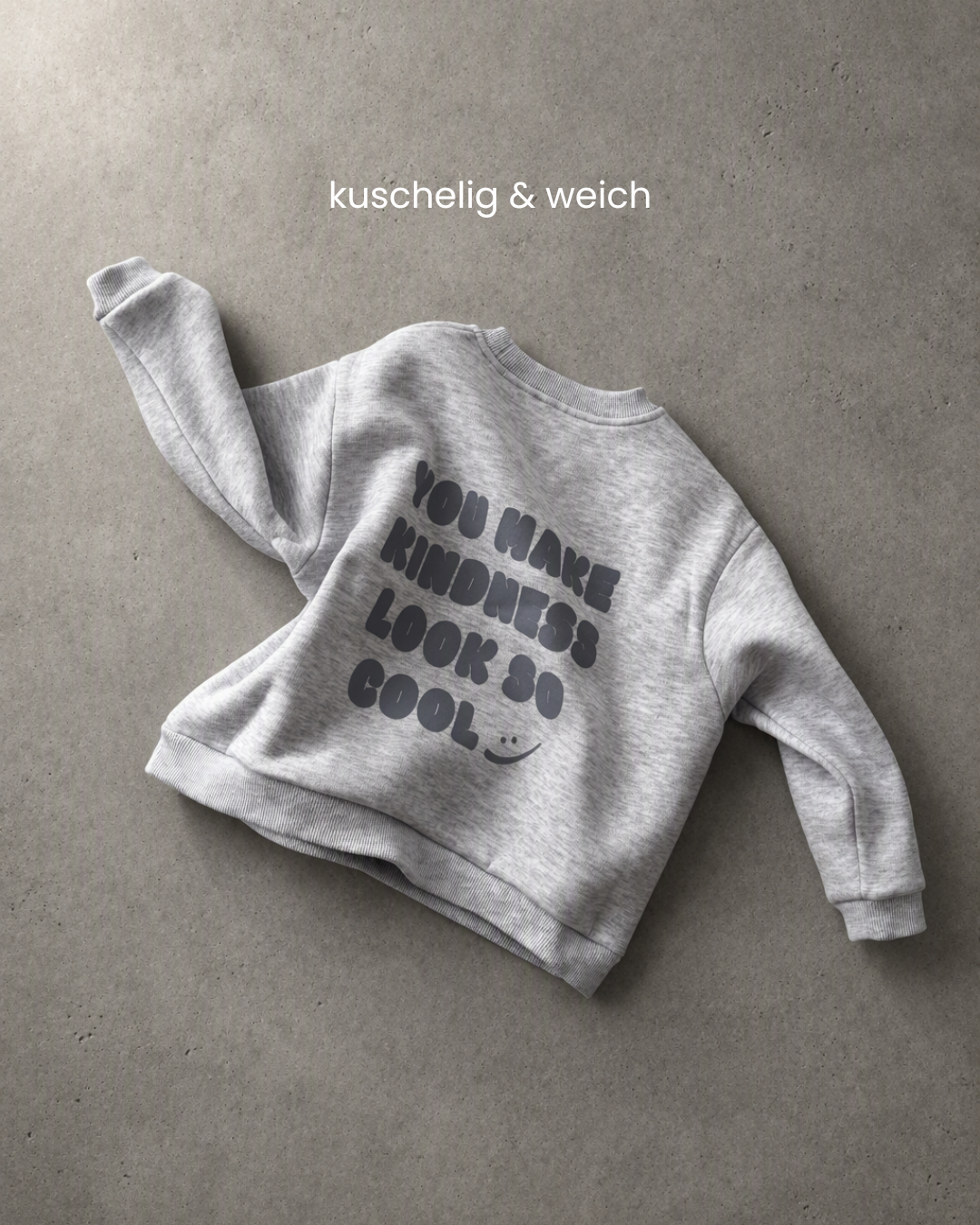Grauer Kindness Sweater von Comfy Studios flach liegend mit Rückenprint und elastischen Bündchen