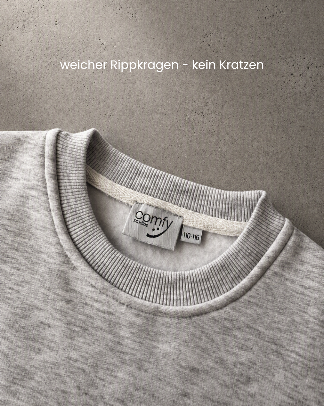 Detailaufnahme des Rippkragens und Comfy Studios Etiketts am grauen Kindness Sweater, Größe 110–116