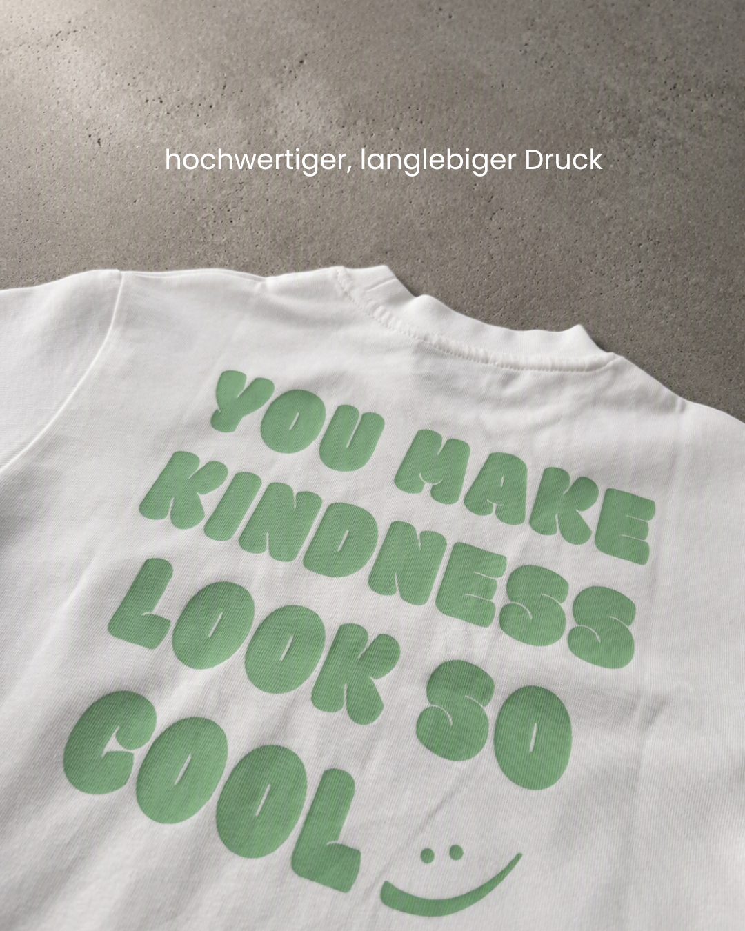 Makro des grünen „You make kindness look so cool"-Prints auf weißer Baumwolle, langlebiger Druck.