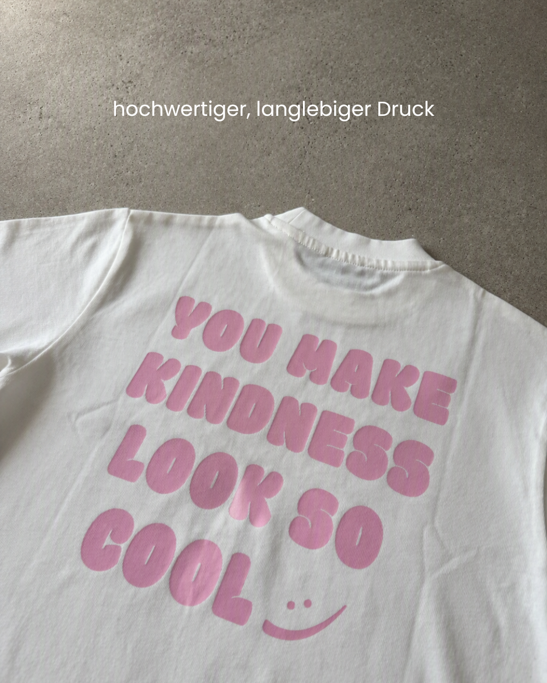 Makroaufnahme des rosa ‚You make kindness look so cool'-Prints auf dem weißen Kinder-T-Shirt.
