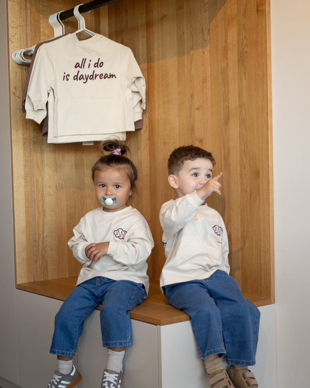 Zwei Kinder in unterschiedlichen Größen im cremefarbenen Daydream Longsleeve, darüber hängt das Oberteil am Bügel.